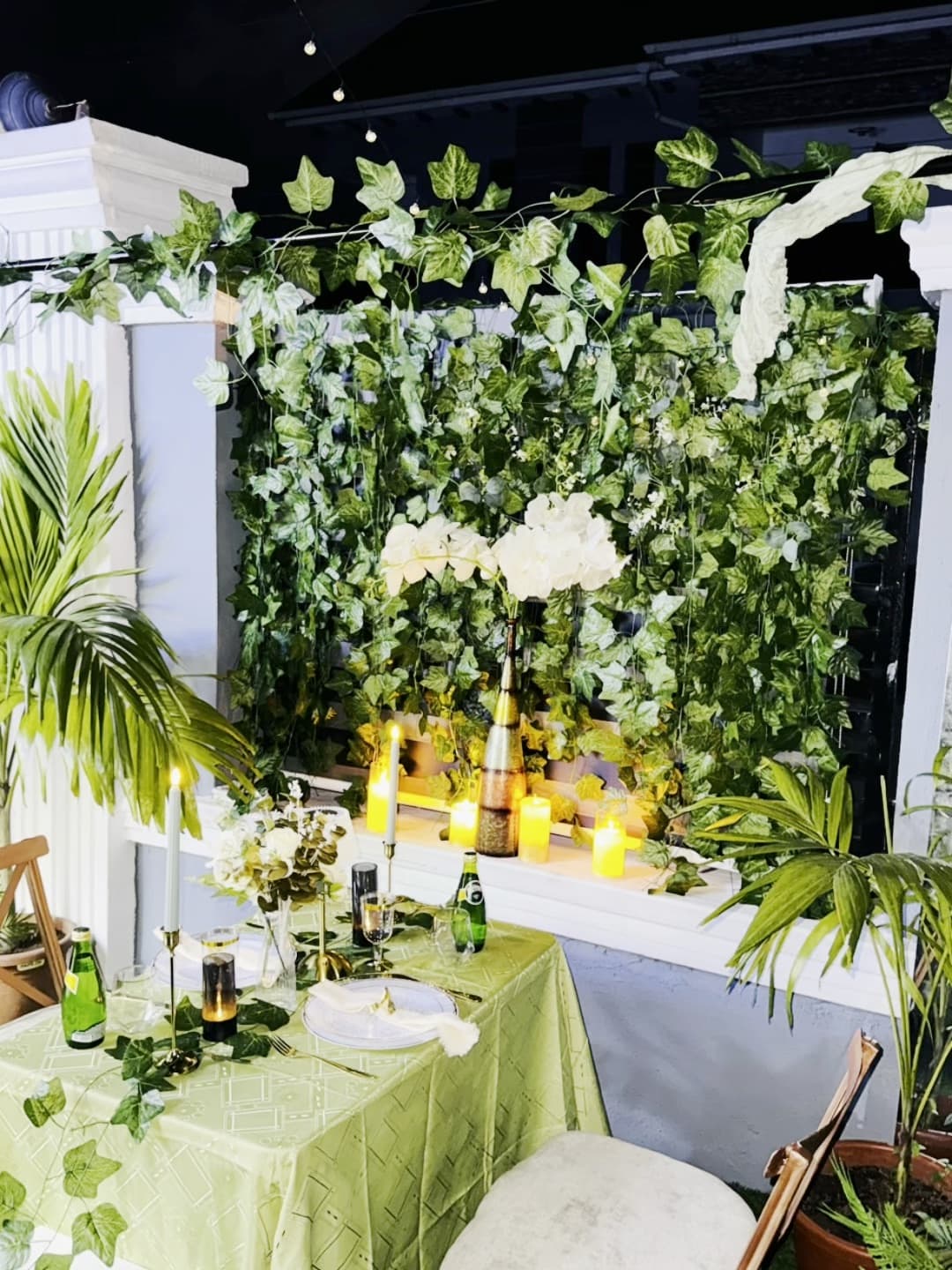 A table for two set for a date night, with candles glowing against a wall of ivy